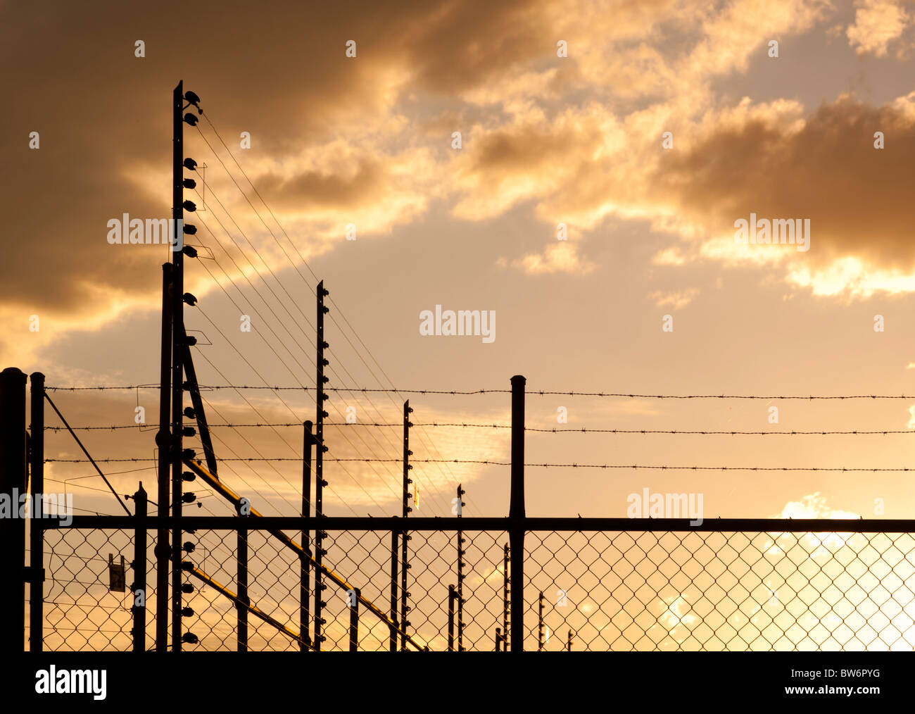 Grandi recinti e filo spinato contro un Cielo di tramonto con spazio di copia Foto Stock