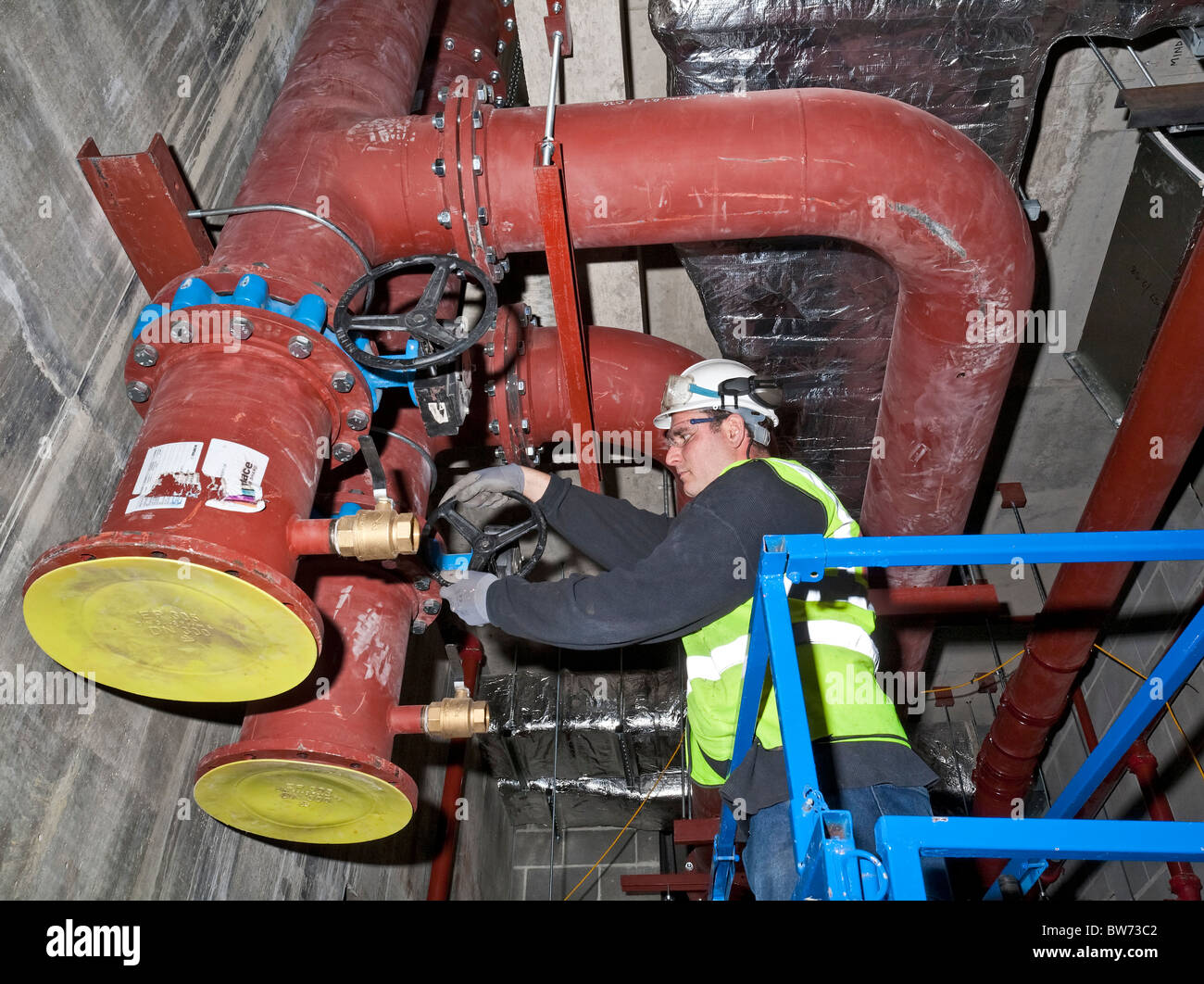 Building services engineer lavorando su tubazioni su un sito di costruzione Foto Stock