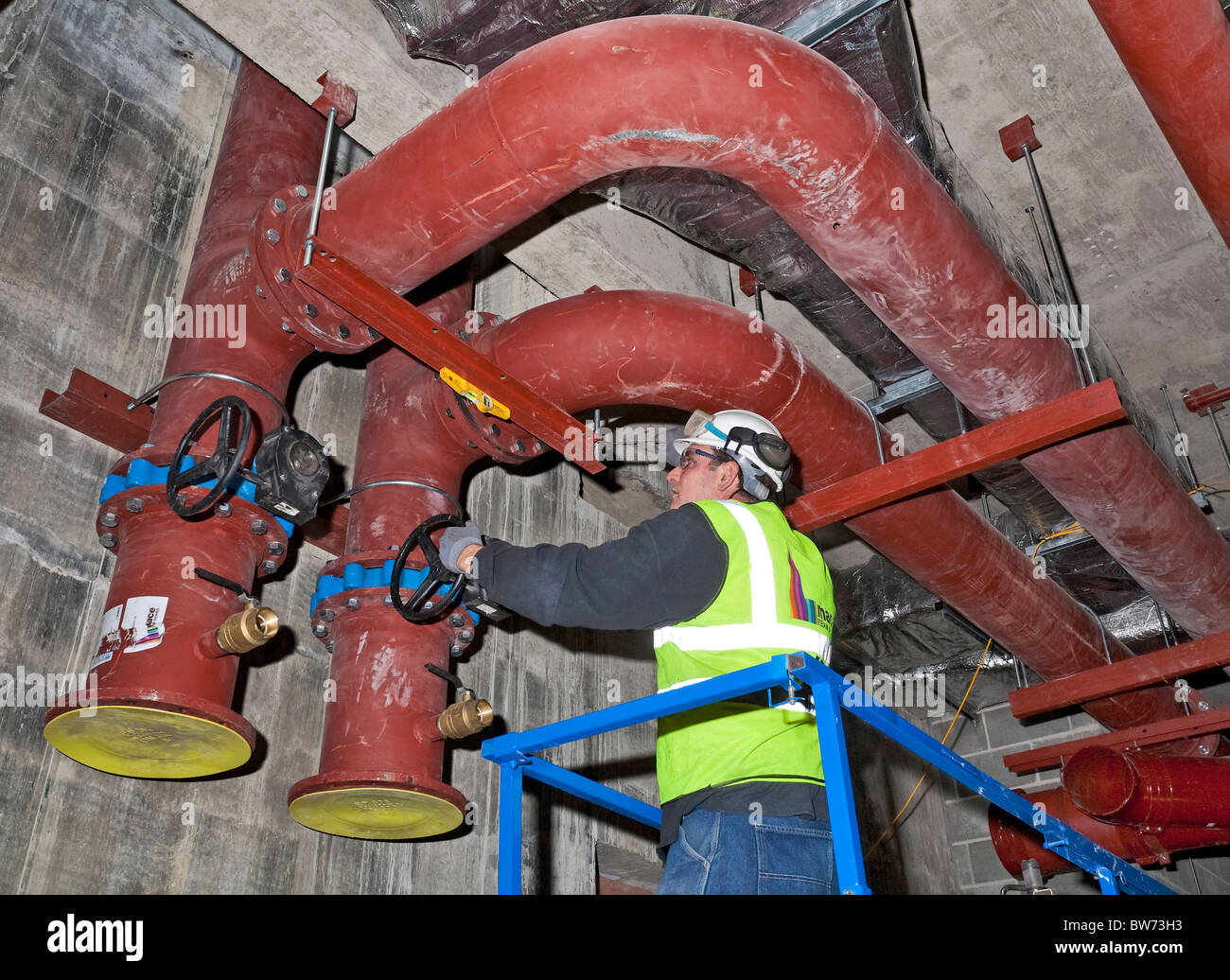 Building services engineer lavorando su tubazioni su un sito di costruzione Foto Stock
