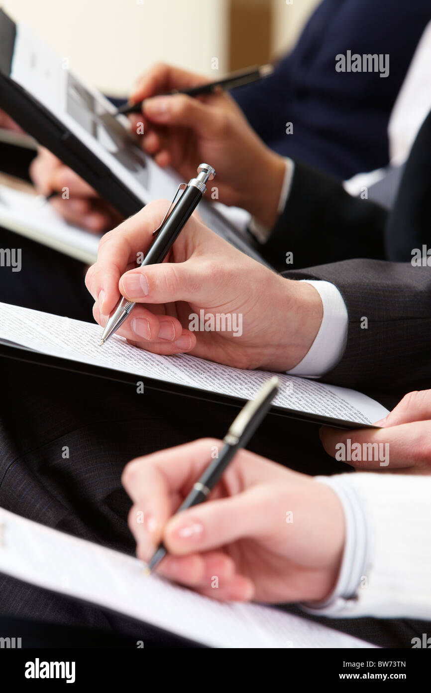 Close-up di persona d'affari mano con la scrittura di documenti durante la conferenza Foto Stock