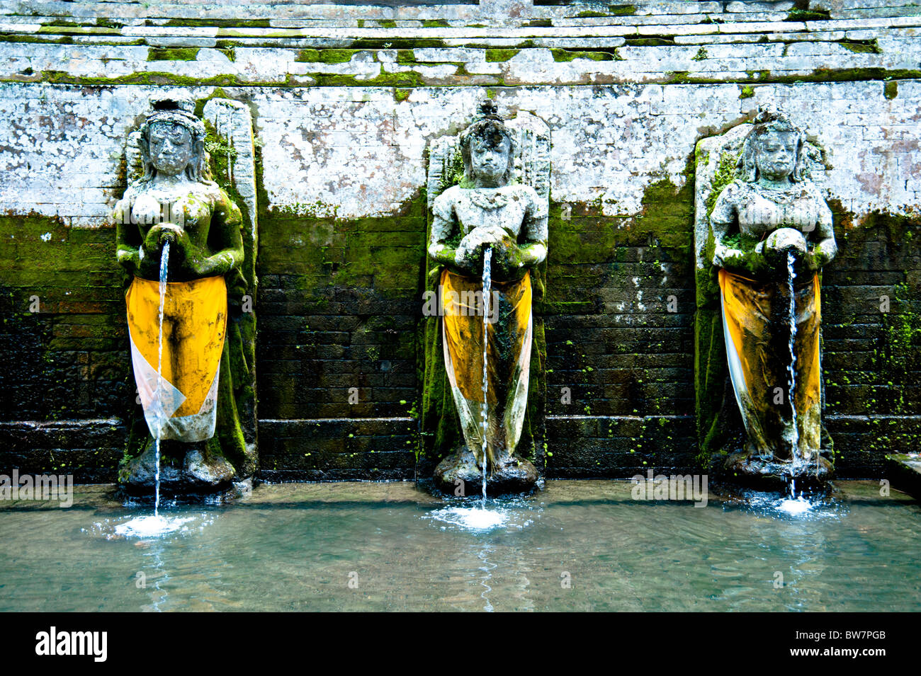 Tre statue nella piscina di balneazione presso la grotta di elefante Bali Indonesia Foto Stock