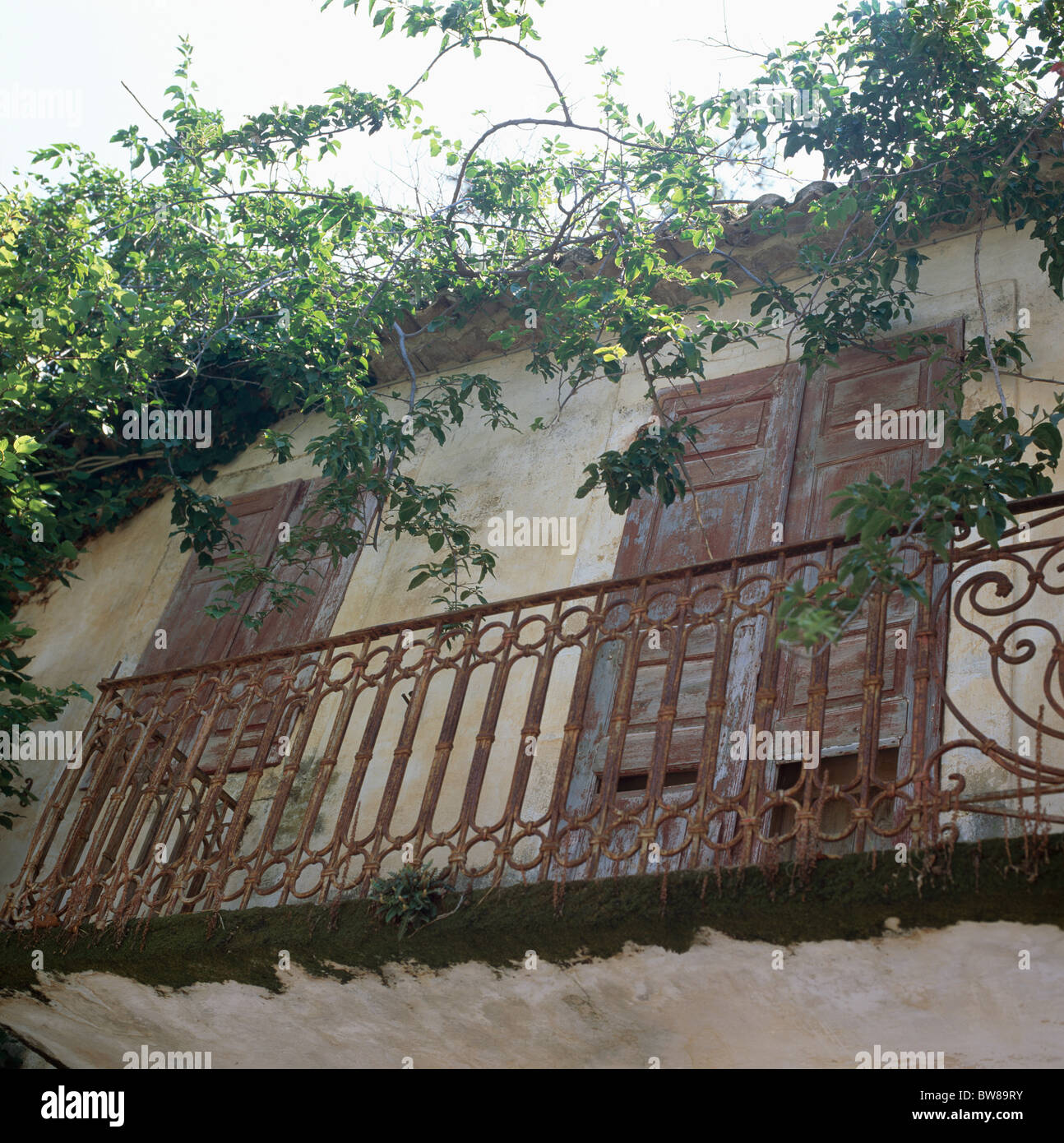 Guardando il ornati in balcone in ferro battuto sulla vecchia casa greca con persiane di legno sulle finestre Francesi Foto Stock