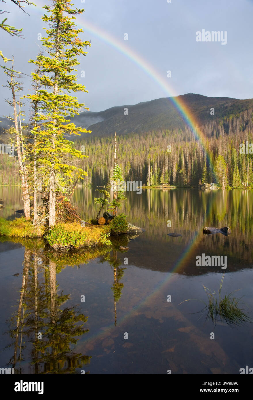 Un arcobaleno è riflessa sulle calme acque di un lago di deserto Foto Stock
