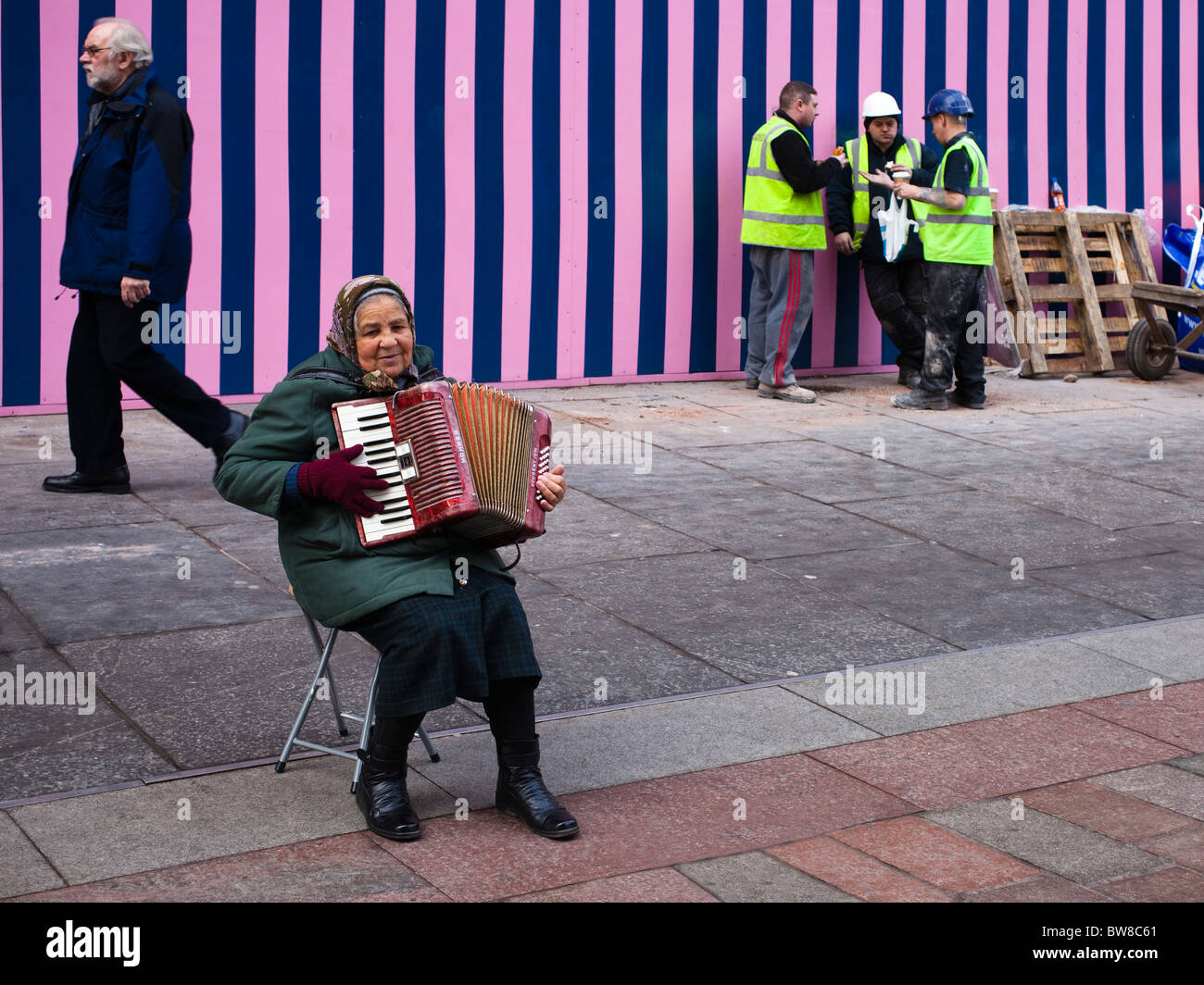 Donna rumena musicista di strada nel centro della città di Glasgow al di fuori di un edificio sito e ignorando tutti i suoi Foto Stock