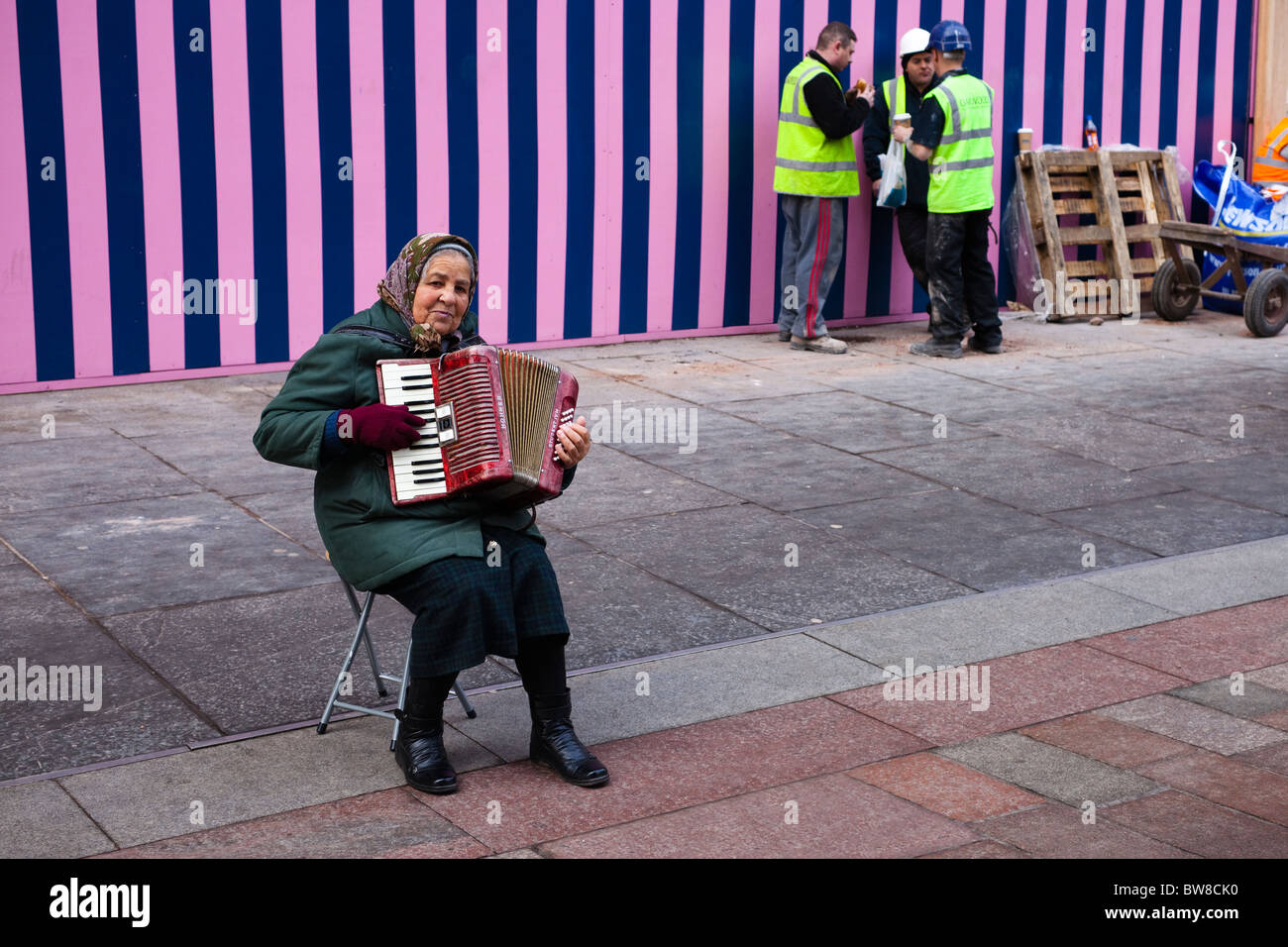 Donna rumena musicista di strada nel centro della città di Glasgow al di fuori di un edificio sito e ignorando tutti i suoi Foto Stock