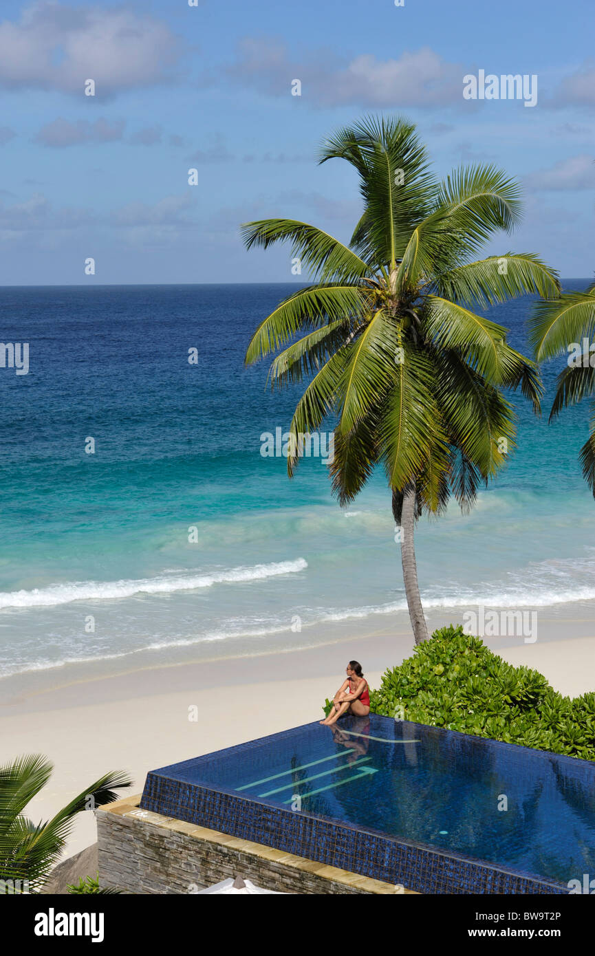 Donna seduta presso la piscina dell'Hotel Banyan Tree, Mahe Island, Seicelle Foto Stock