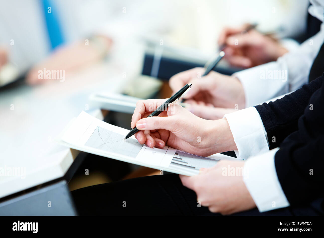 Close-up di persona d'affari le mani con la scrittura del documento durante la conferenza Foto Stock