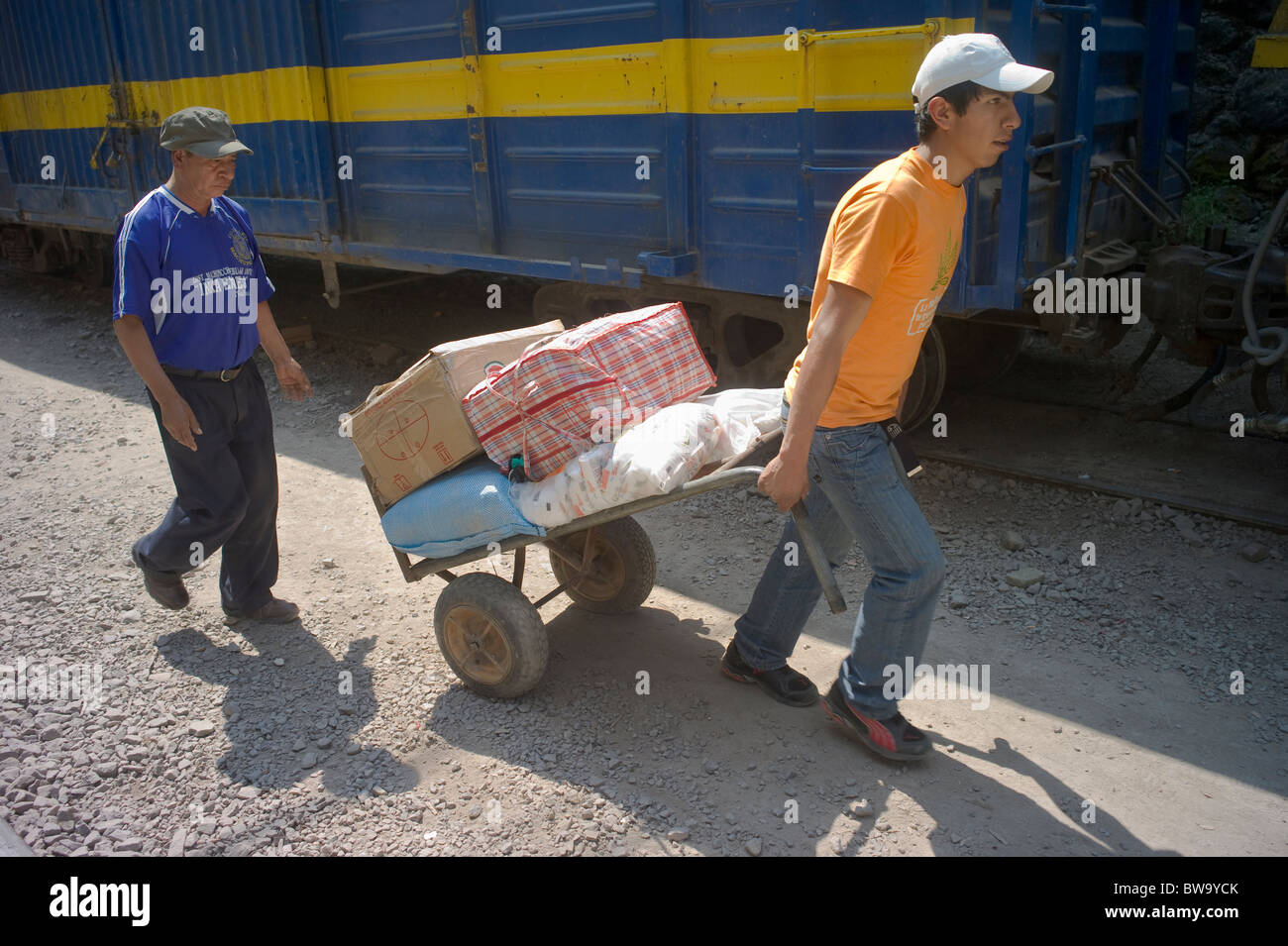 L'uomo puling merci su un carrello scarico di un treno, Agua Calientes, Perù Foto Stock