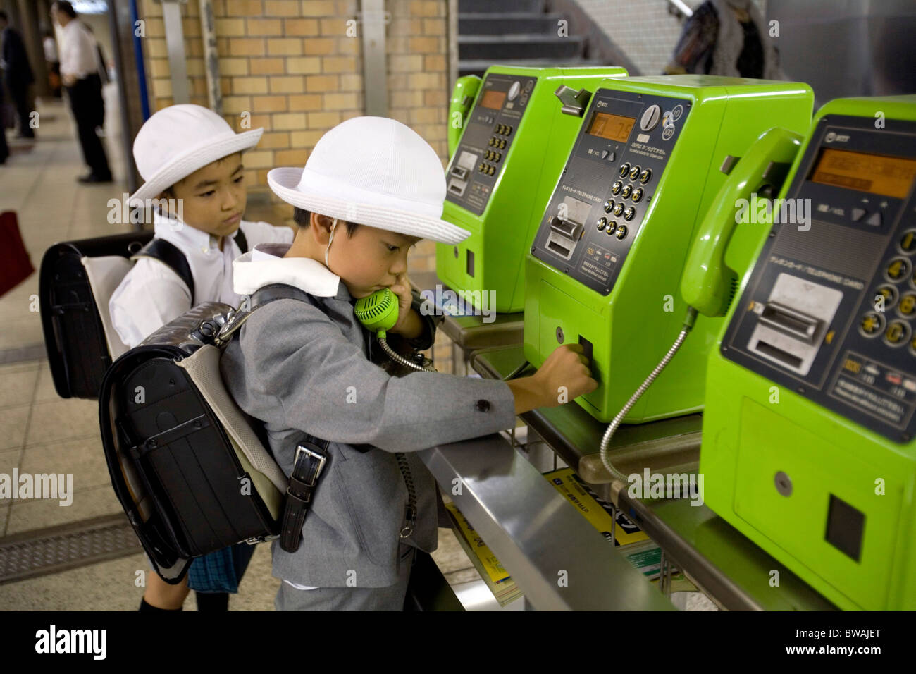 Scolaro giapponese chiamando da un telefono pubblico nella metropolitana di Tokyo, Giappone Foto Stock