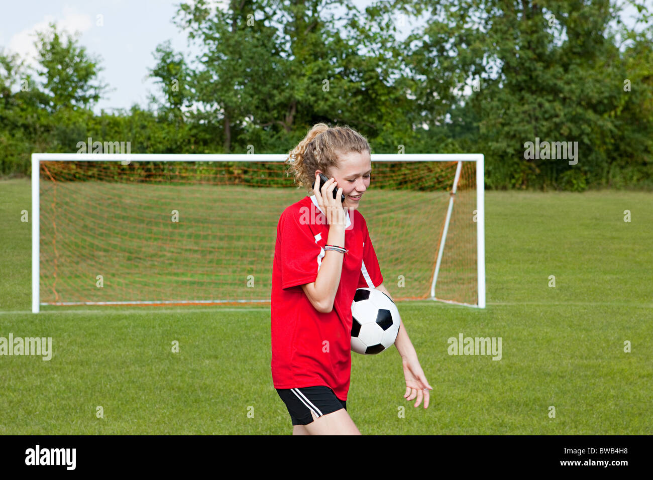 Girl soccer player utilizzando il cellulare Foto Stock