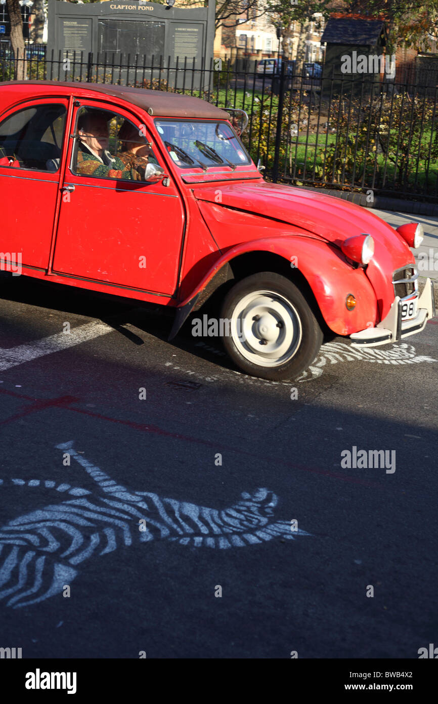 Croce di zebra zebra graffiti su asfalto e auto classica Foto Stock