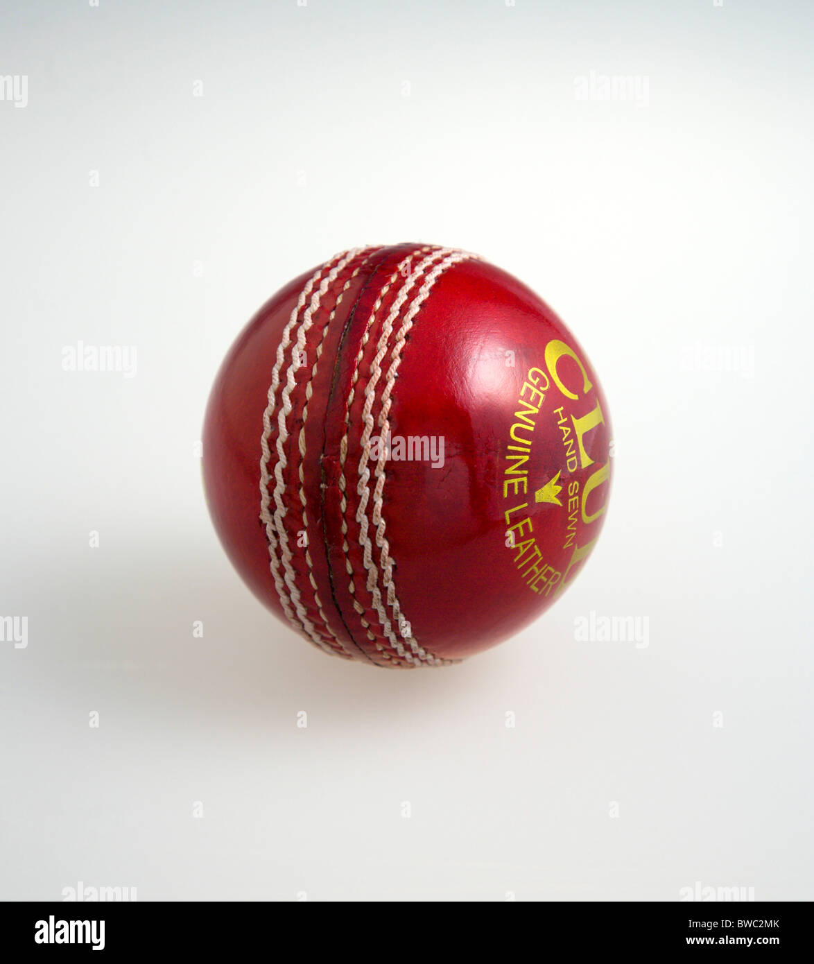 Sport, giochi con la palla, cricket, rosso cucito a mano in pelle di sfera di cricket su uno sfondo bianco. Foto Stock