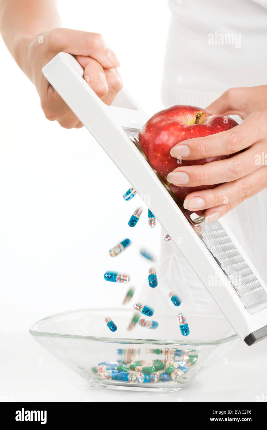 Close-up di vitamine e pillole riversandosi nel vaso mentre il reticolo femmina rosso apple Foto Stock