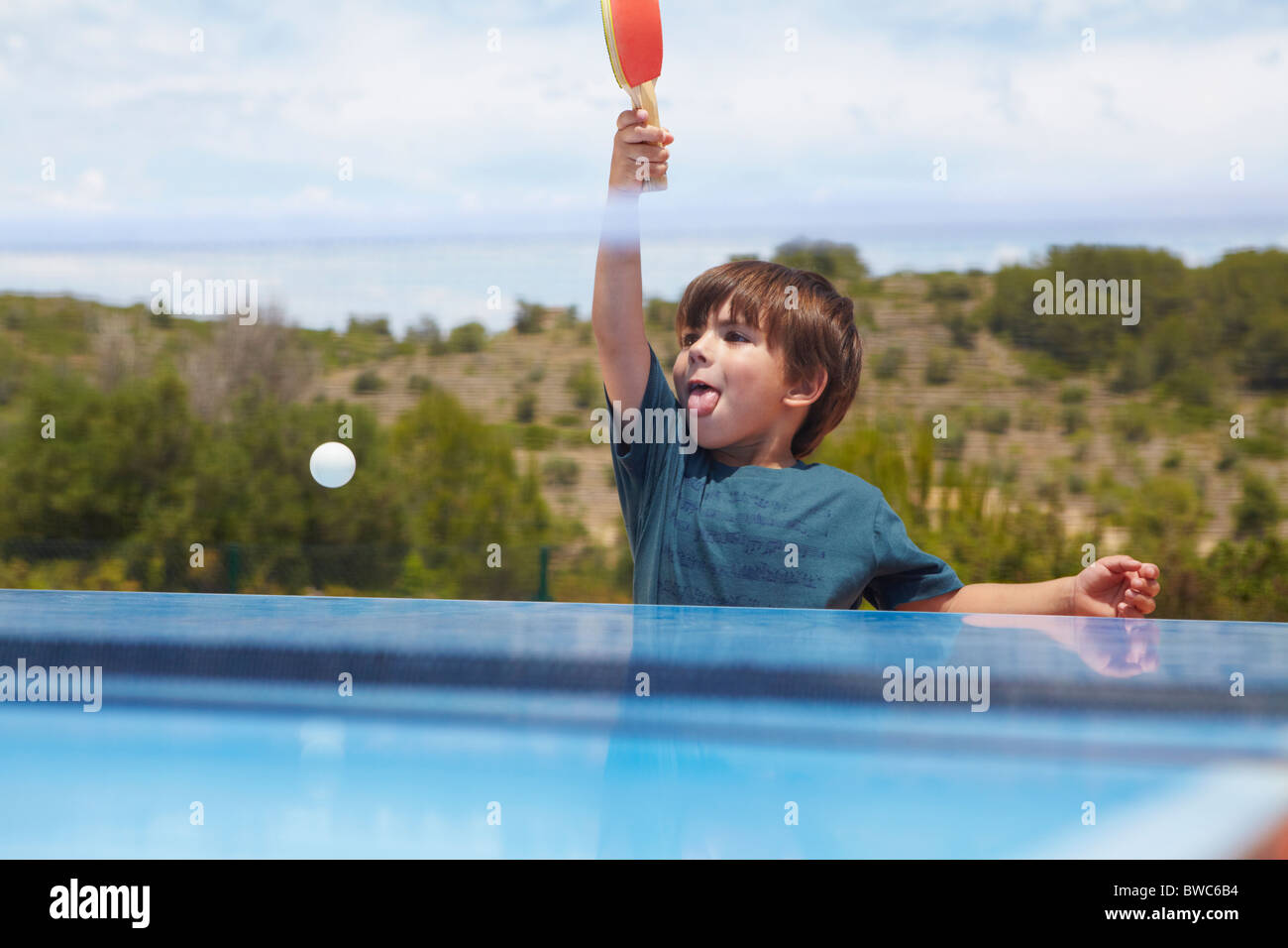 Giovane ragazzo giocando a ping-pong all'aperto Foto Stock