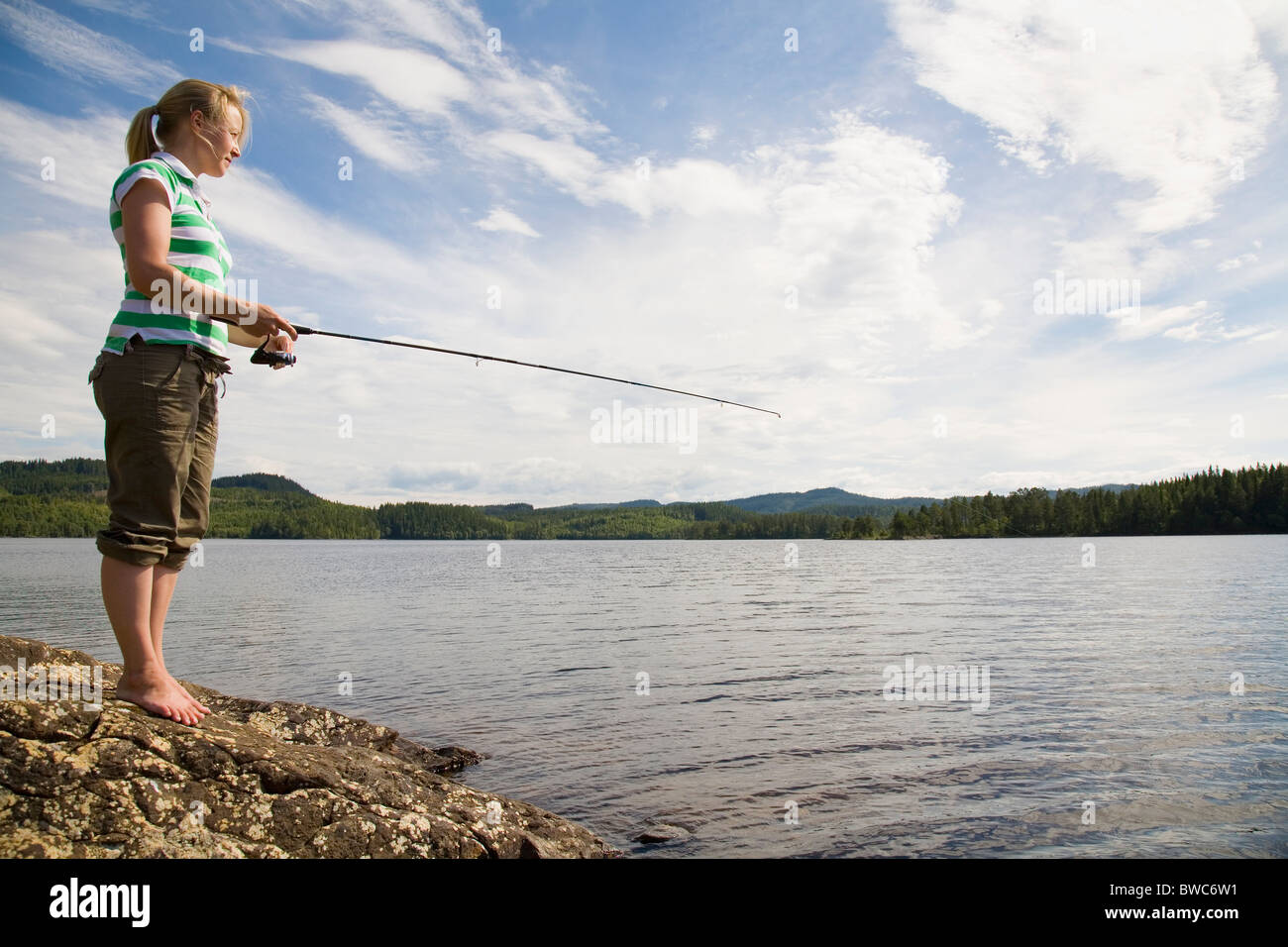 Giovane donna pesca nel lago Foto Stock