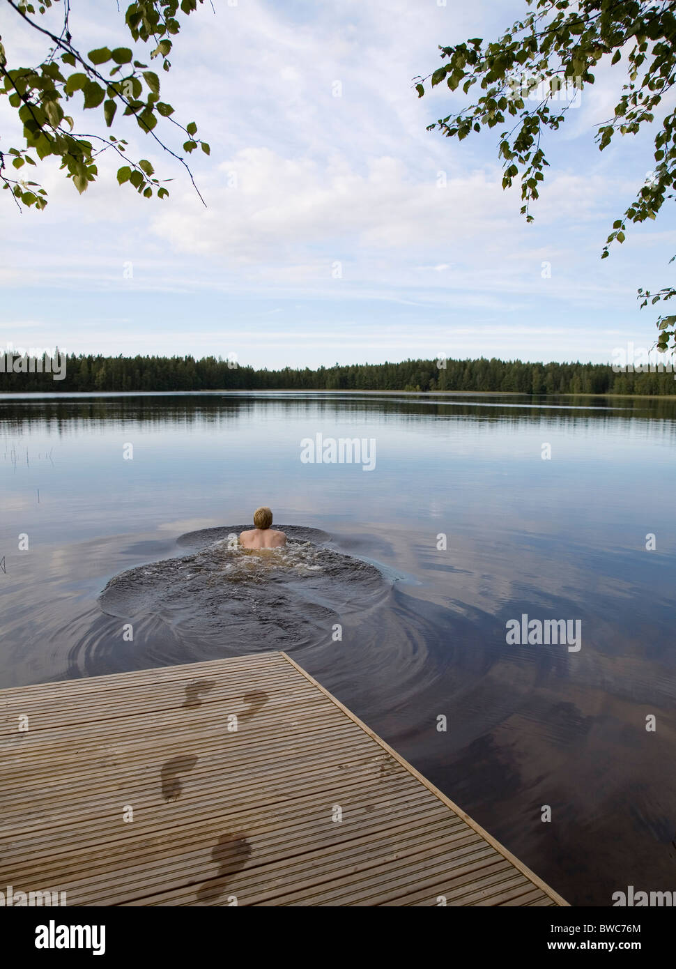 L'uomo nuotare nel lago ancora Foto Stock