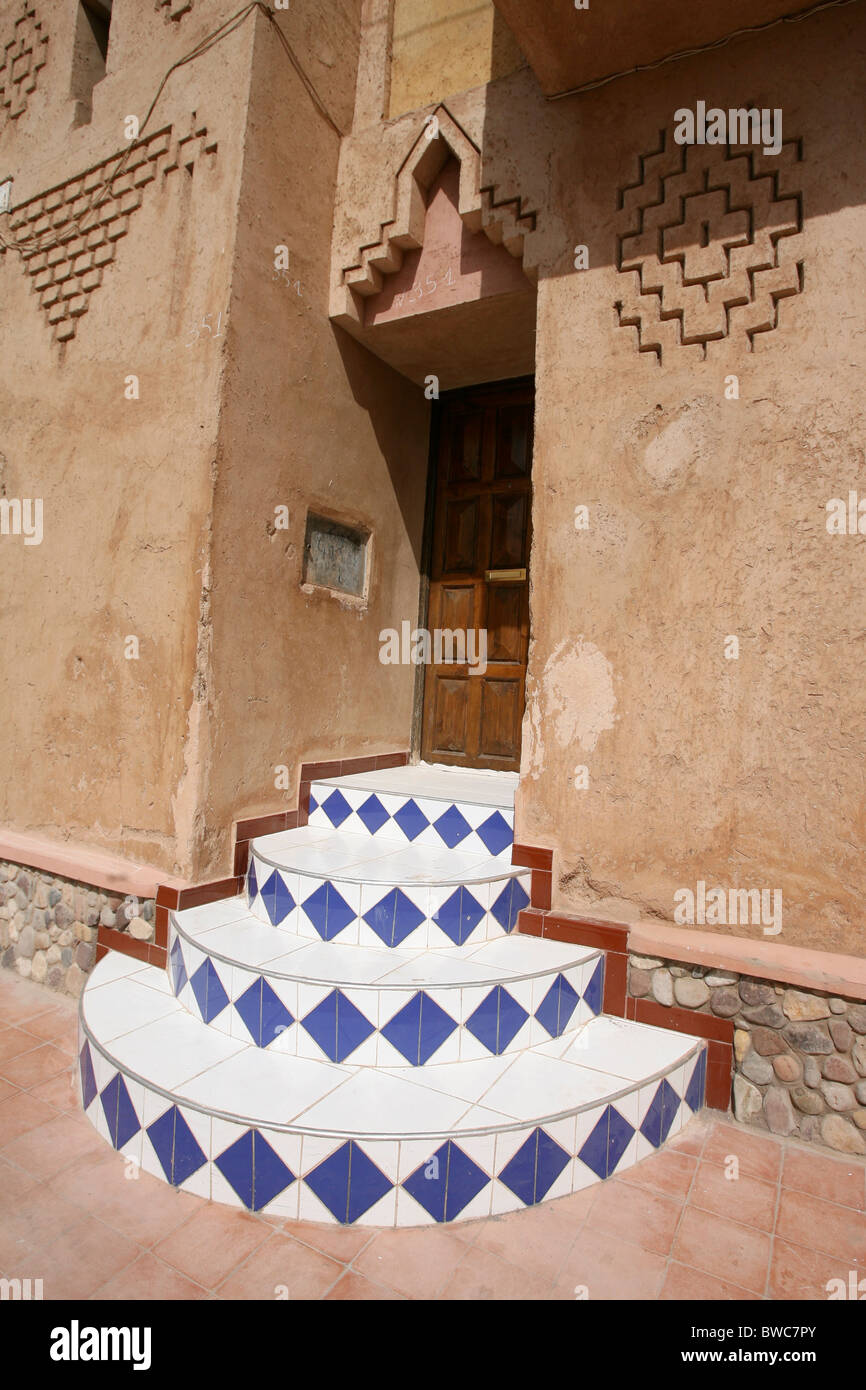 In piastrelle colorate gradini che conducono ad una porta di legno in una città del Marocco Foto Stock