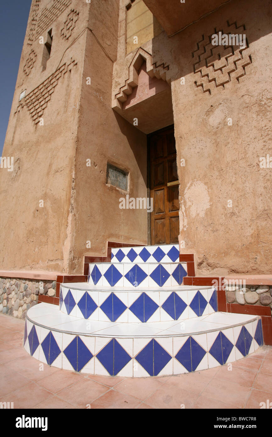 In piastrelle colorate gradini che conducono ad una porta di legno in una città del Marocco Foto Stock