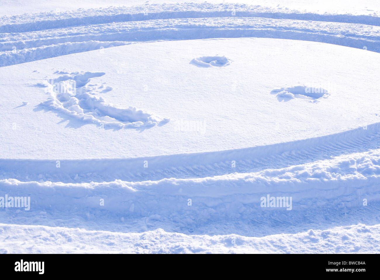 Immagine del viso rotondo con gli occhi e il sorriso disegnato sulla neve Foto Stock