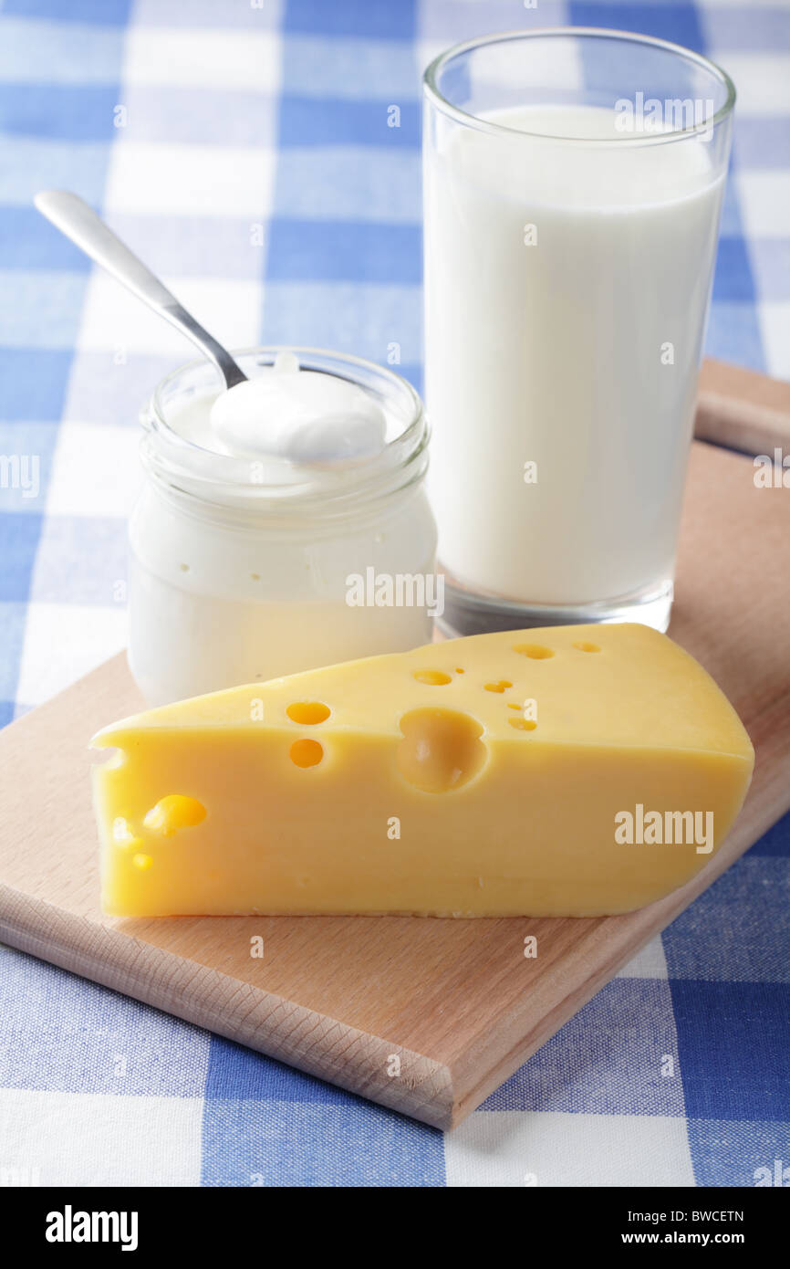 Formaggio giallo, una tazza di latte e il vaso con panna acida Foto Stock