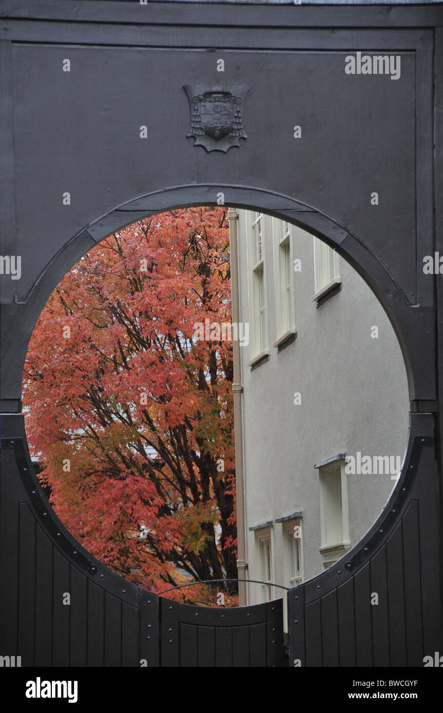 Visualizzazione attraverso l'apertura rotonda in gate ad un edificio di Oxford in contrasto con foglie di autunno in background. Oxford, Oxfordshire, England, Regno Unito Foto Stock