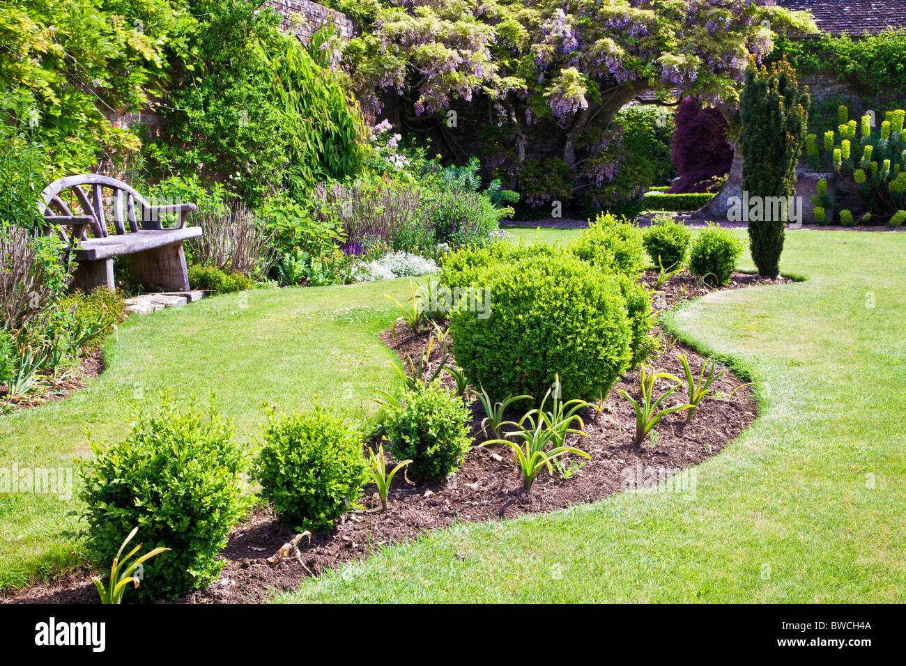 Un ondulato impianto borderand set letto nel prato di un grande paese inglese giardino d'estate. Foto Stock
