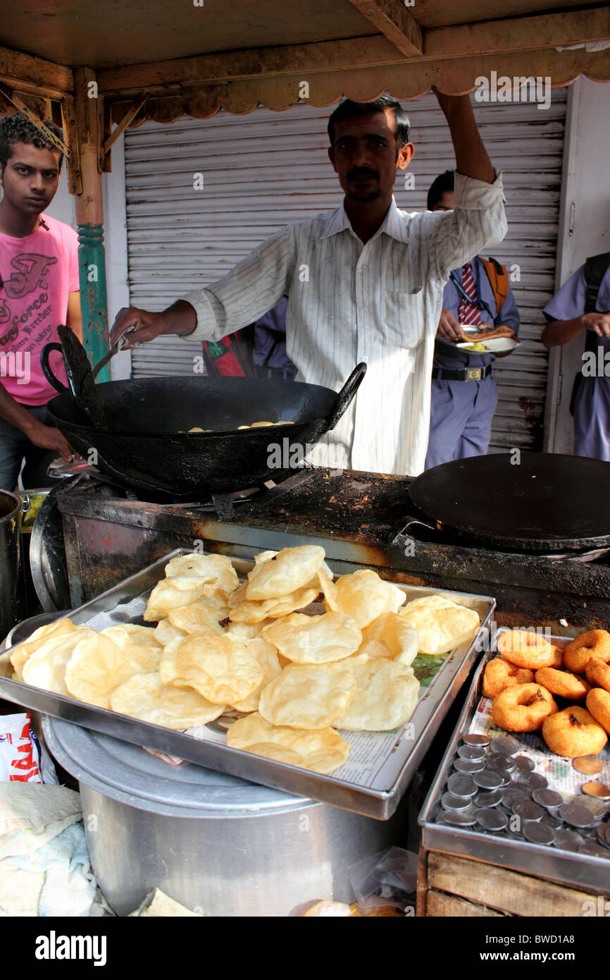 Pressione di stallo di strada in India di vendita di alimenti con i giovani e scolari in uniforme di mangiare Foto Stock