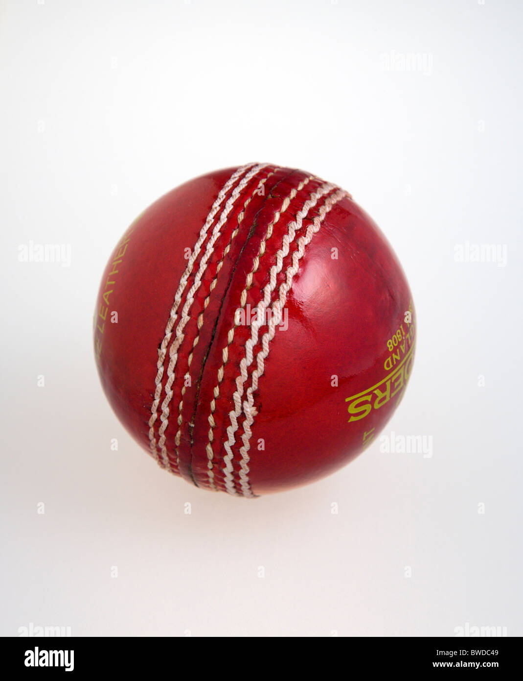 Sport, giochi con la palla, cricket, rosso cucito a mano in pelle di sfera di cricket su uno sfondo bianco. Foto Stock