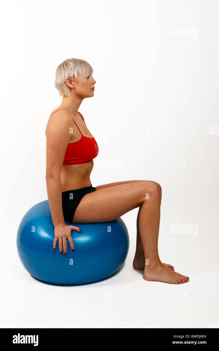 Giovane donna usando un swiss palla e utilizzarlo per migliorare il suo core muscoli Foto Stock