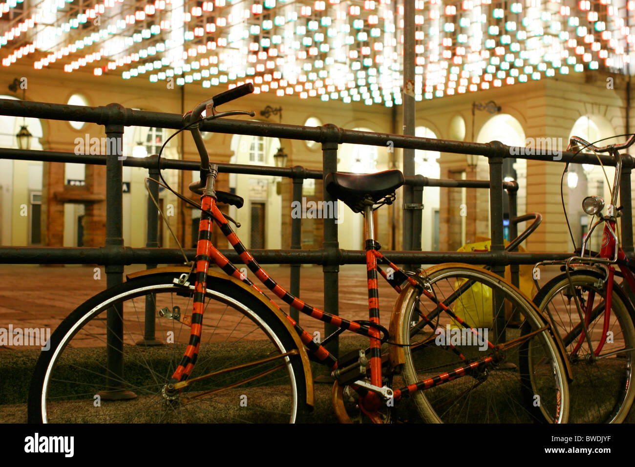 Biciclette parcheggiate legate alla recinzione nel centro di Torino di notte Foto Stock