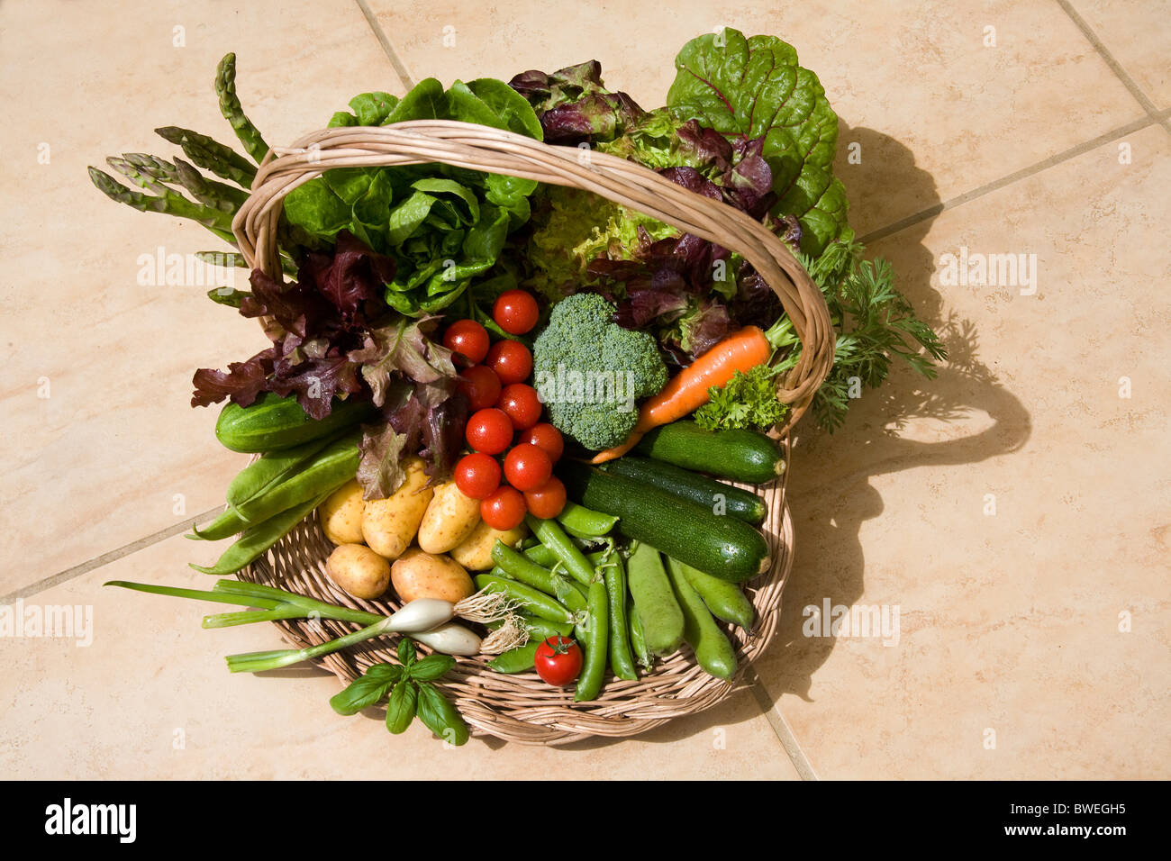 Deliziosa coltivati localmente appena picket British in primavera ed estate la verdura in un cesto su un pavimento di piastrelle in Weald of Kent REGNO UNITO Foto Stock