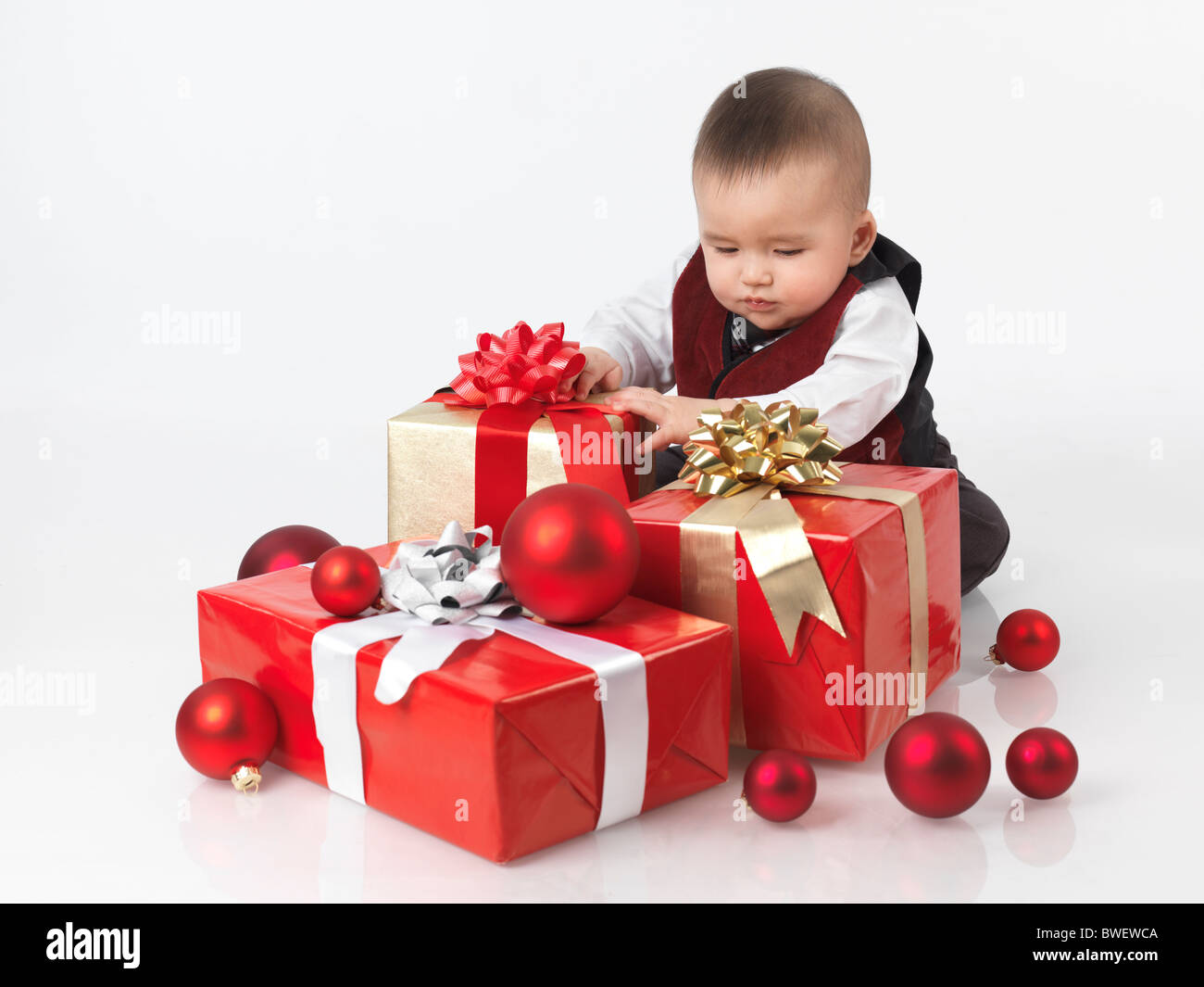 Sei mesi baby boy di aprire i regali di Natale. Isolato su sfondo bianco. Foto Stock