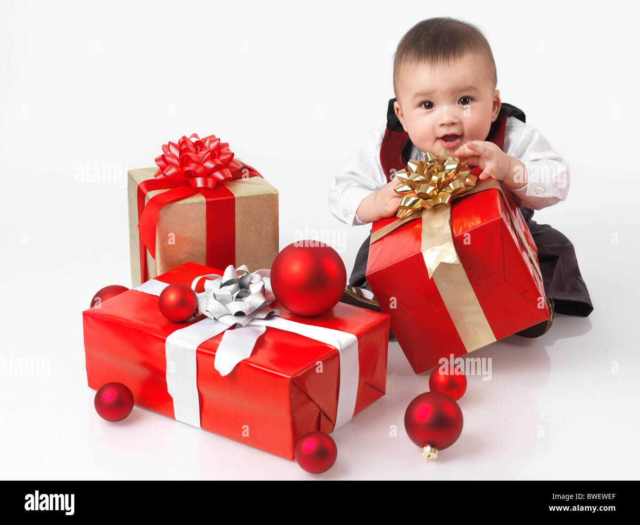 Felice sei mesi baby boy di aprire i regali di Natale. Isolato su sfondo bianco. Foto Stock