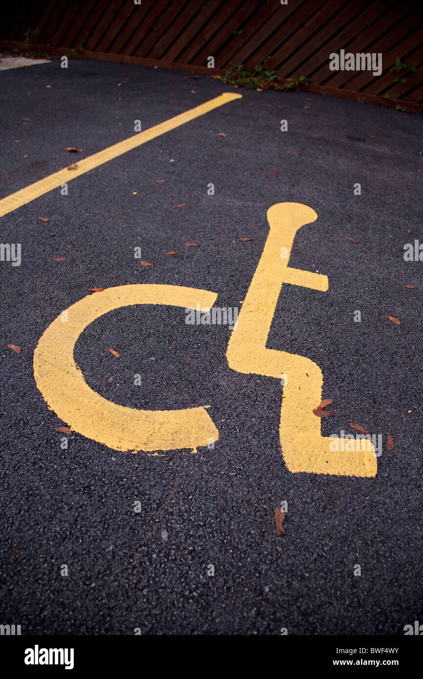 Sedia a rotelle disabili legati persona simbolo sulla pista di un bollino blu lo spazio per parcheggiare in un parcheggio Foto Stock