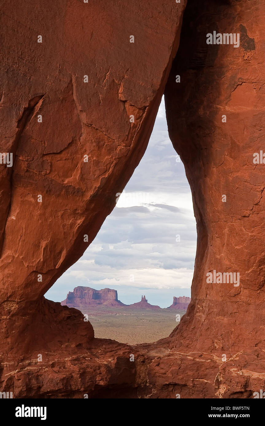 Guardando attraverso la caduta di strappo arco verso la Mesas nella Monument Valley, Arizona, Stati Uniti d'America Foto Stock