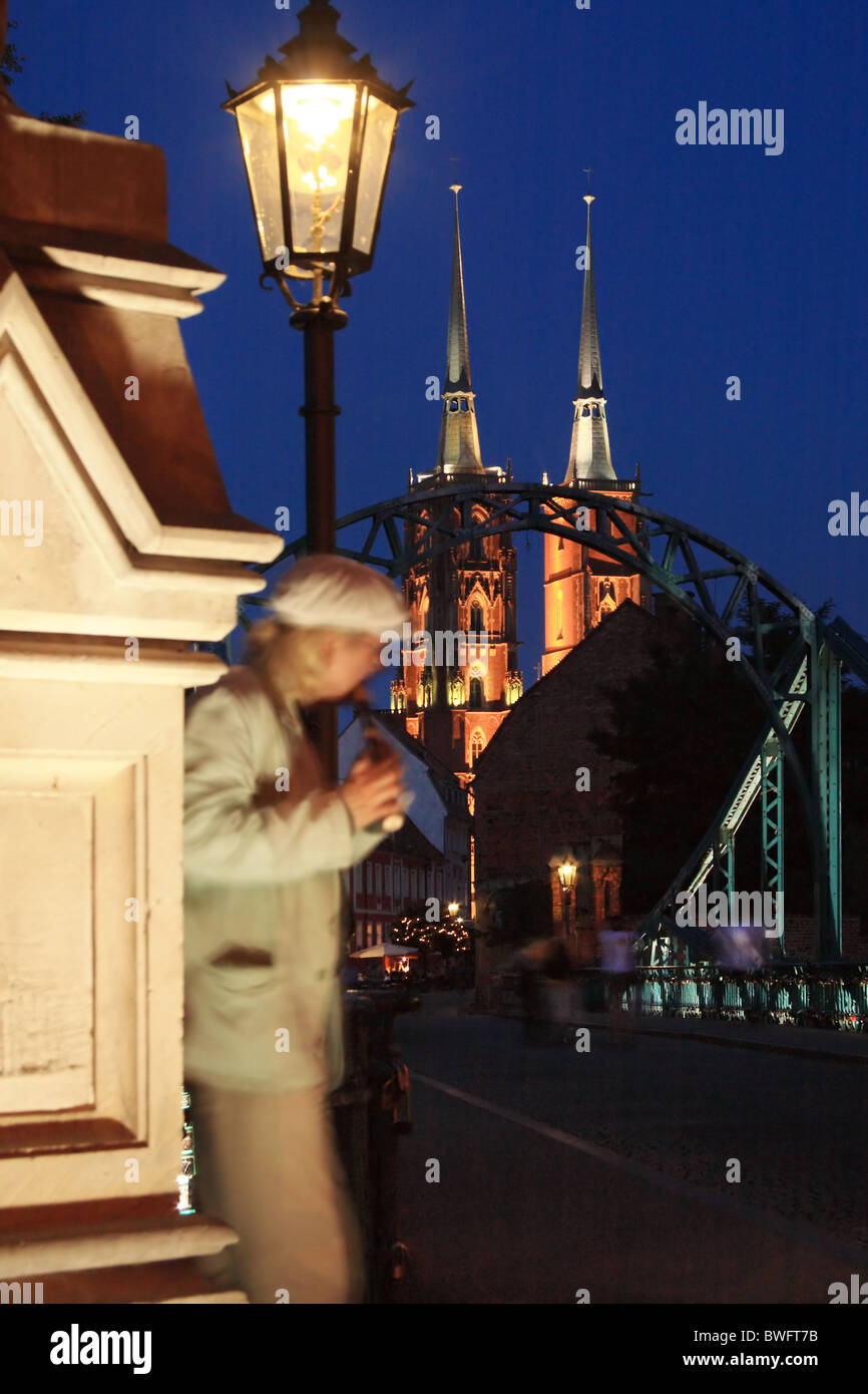 Busker suonare il flauto Tumski sul ponte, Cattedrale di San Giovanni Battista in background. Wroclaw, Bassa Slesia, Polonia. Foto Stock