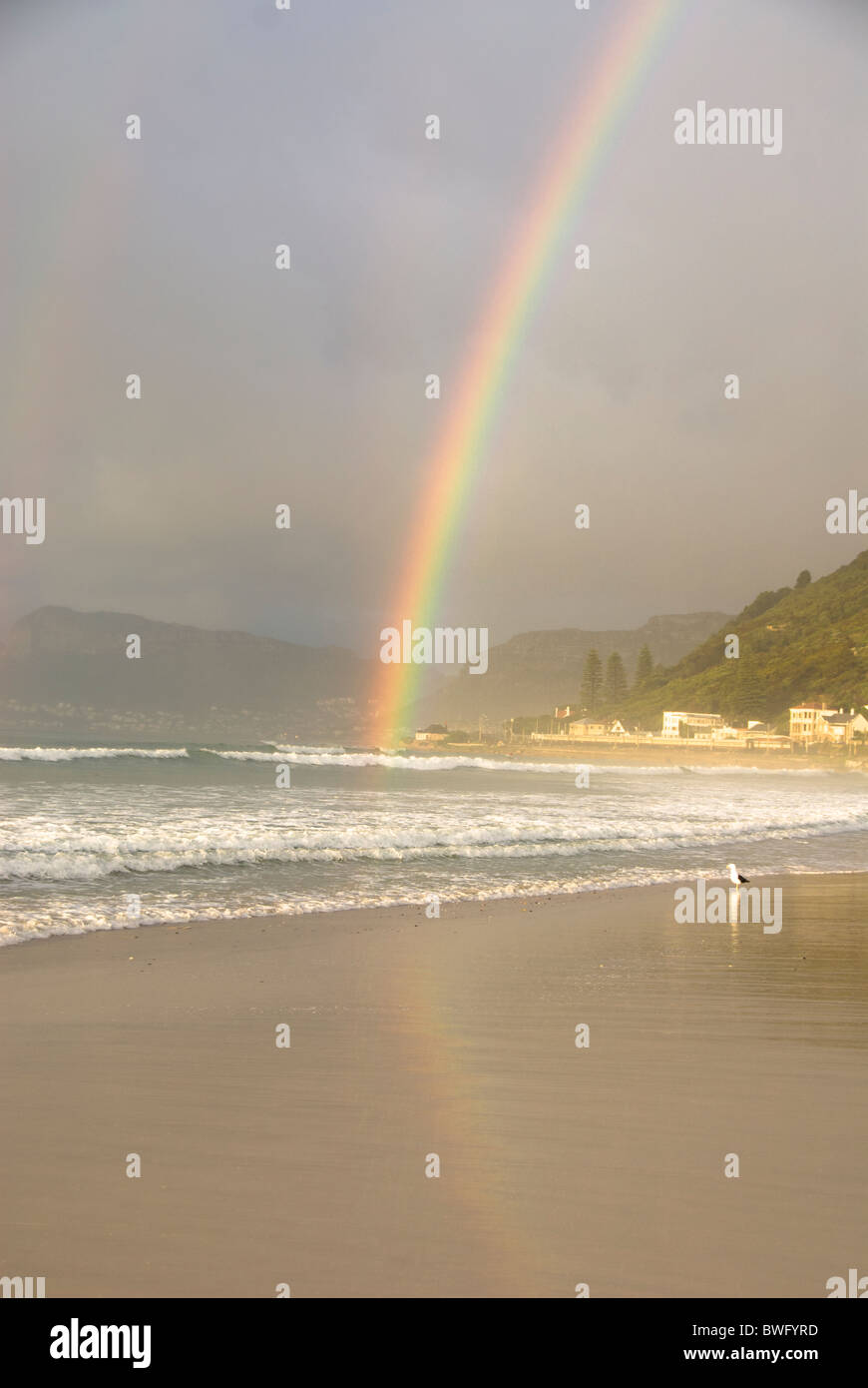 Rainbow su Kalk Bay montagne e Muizenberg Beach a sunrise, Muizenberg Beach, Cape Peninsula, Western Cape, Sud Africa Foto Stock