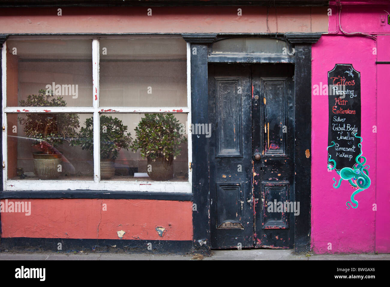 Sbiadita eleganza di un salone di bellezza che offre tatuaggi, piercing, organismo di gioielli a Youghal, County Cork, Irlanda meridionale Foto Stock