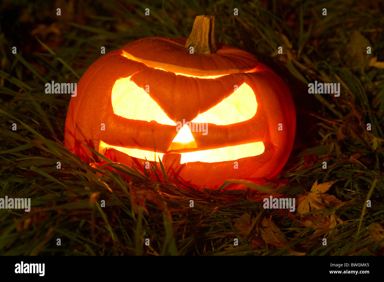 Illuminata la zucca di halloween jack-o-lantern su erba di notte Foto Stock