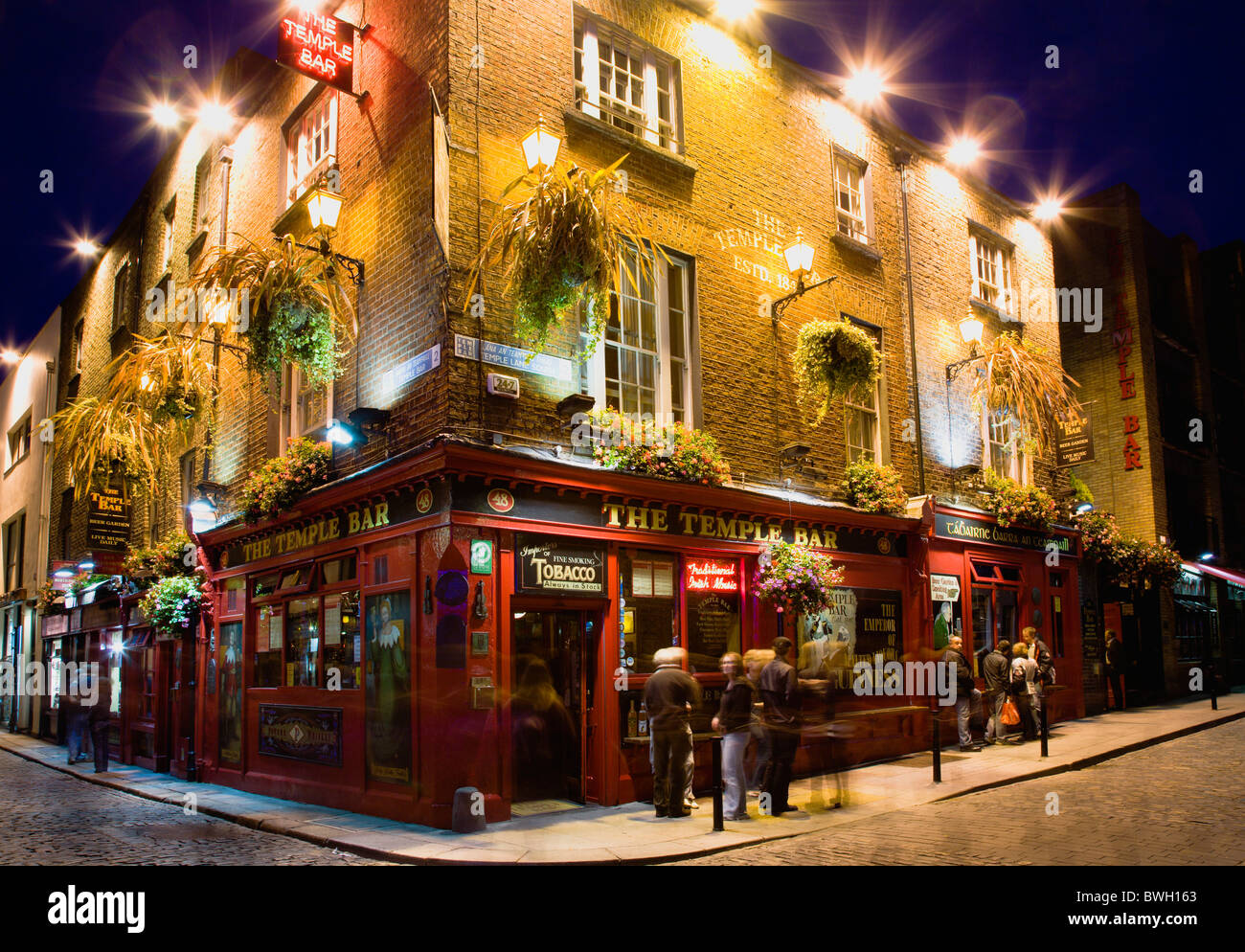 L'Irlanda County Dublin City pub Temple Bar illuminato di notte con la  gente che camminava passato sulle strade di ciottoli Foto stock - Alamy