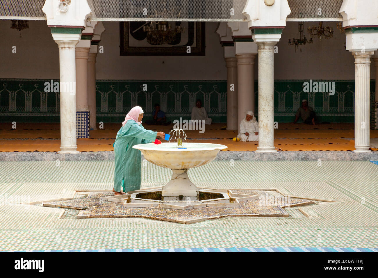 Una femmina adoratore islamica deterge se stessa ad un abluzione fontana a una moschea nella Medina, la città vecchia di Fes, Marocco. Foto Stock