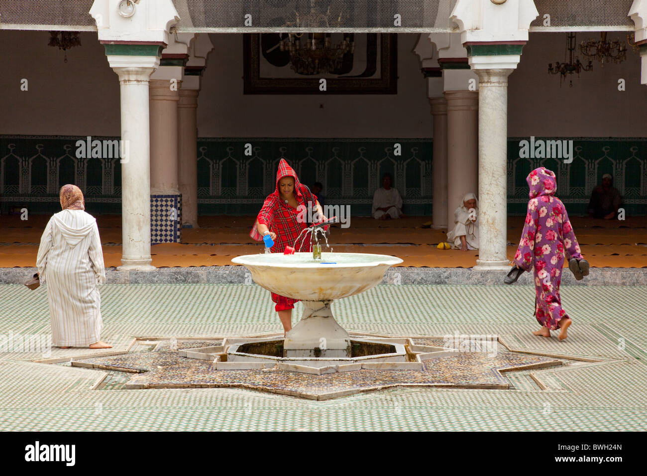 Femmina islamica adoratori di purificare se stessi in corrispondenza di una abluzione fontana a una moschea nella Medina, la città vecchia di Fes, Marocco. Foto Stock