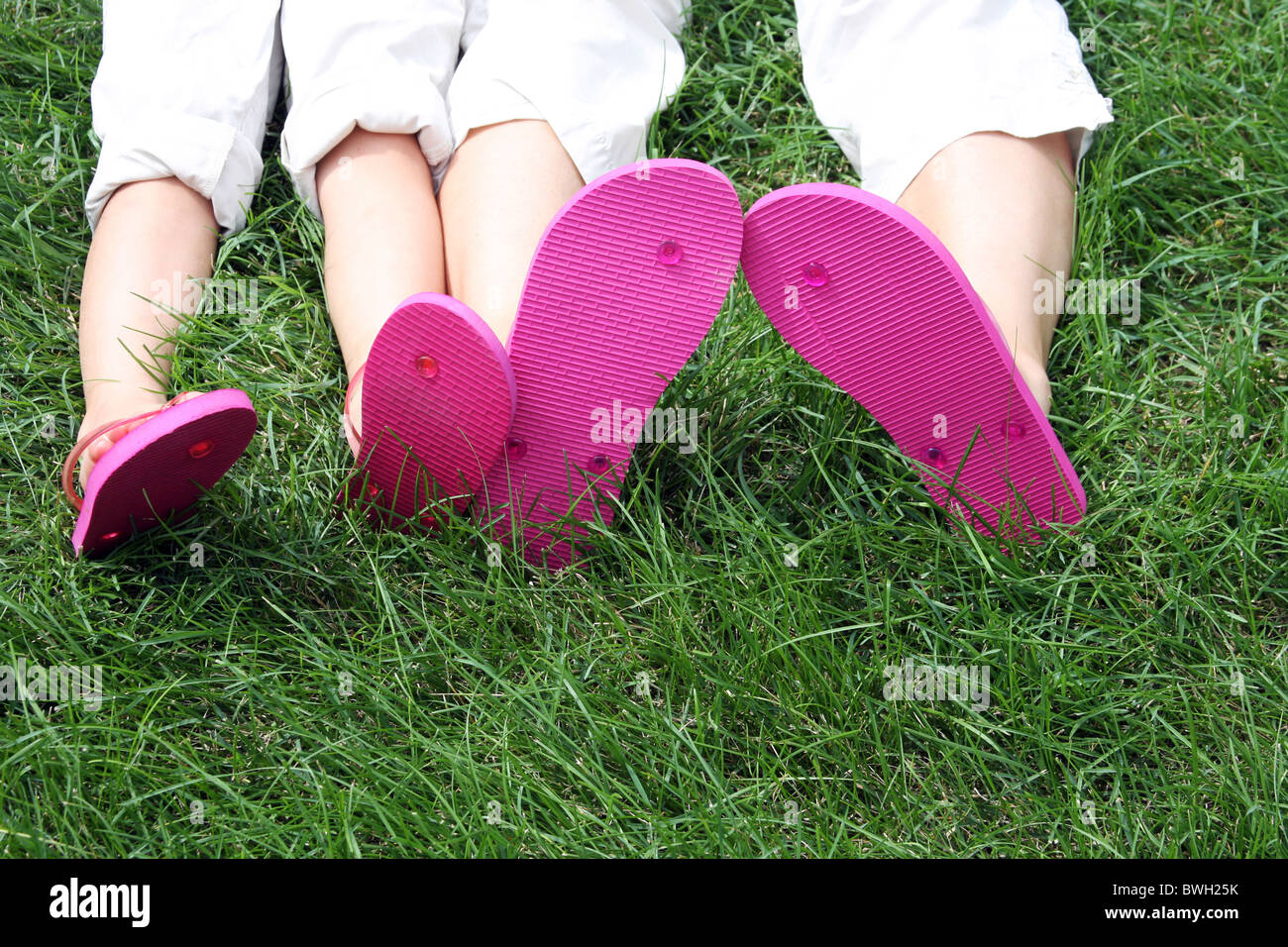 Una donna e bambino flip flop posa in erba Foto Stock