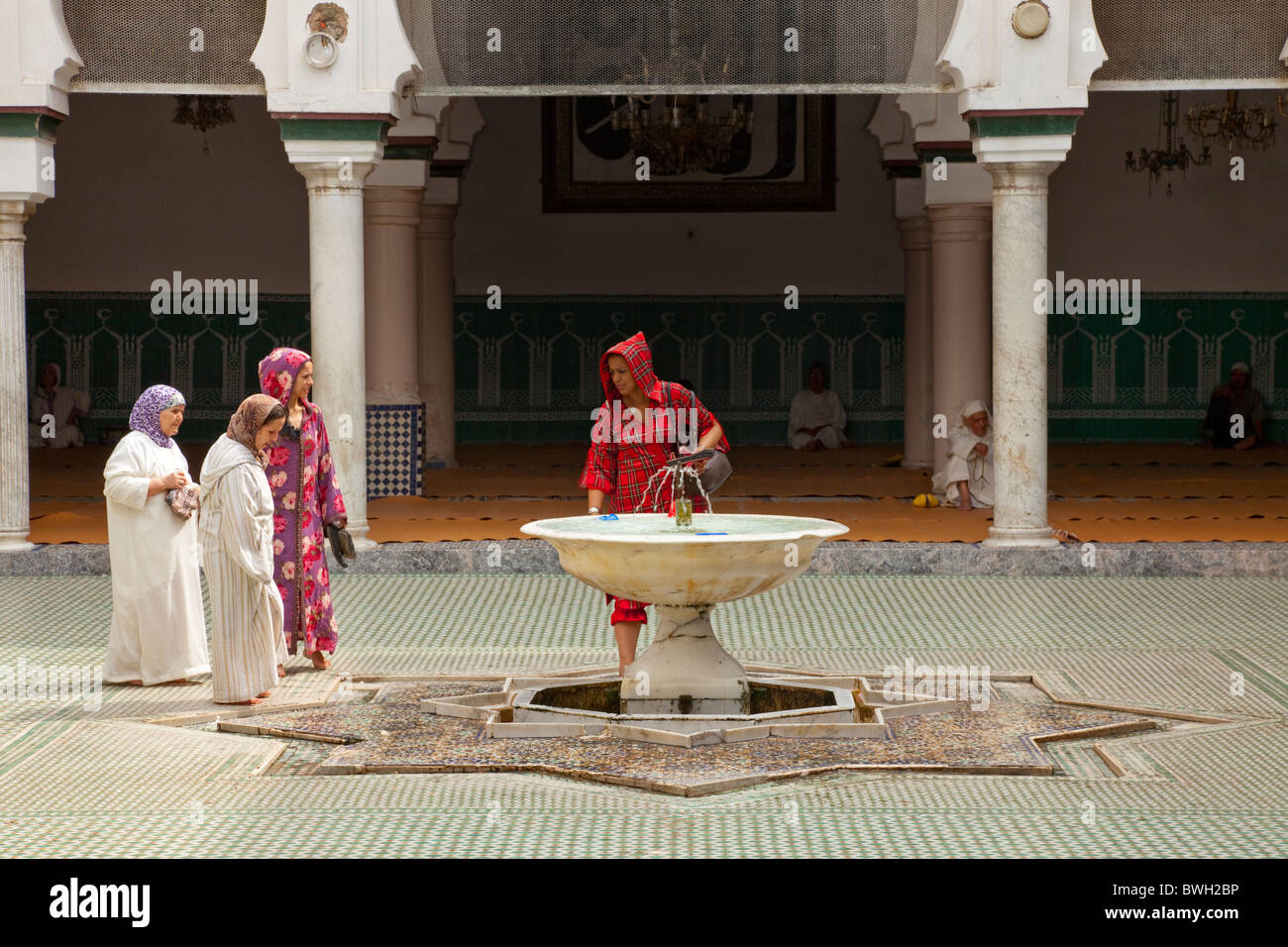 Islamico femmina adoratori di purificare se stessi in corrispondenza di una abluzione fontana a una moschea nella Medina, la città vecchia di Fes, Marocco. Foto Stock