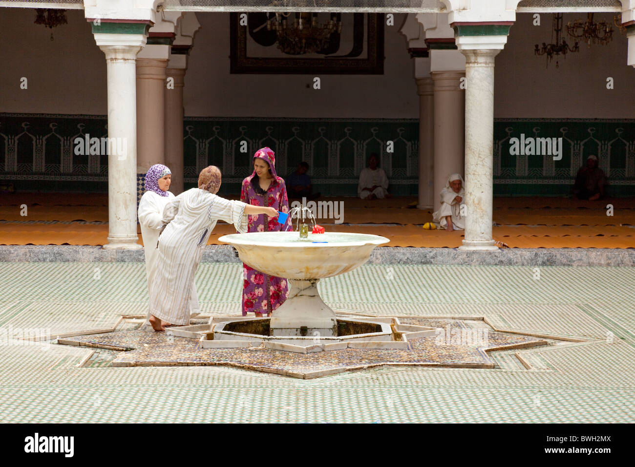 Islamico femmina adoratori di purificare se stessi in corrispondenza di una abluzione fontana a una moschea nella Medina, la città vecchia di Fes, Marocco. Foto Stock