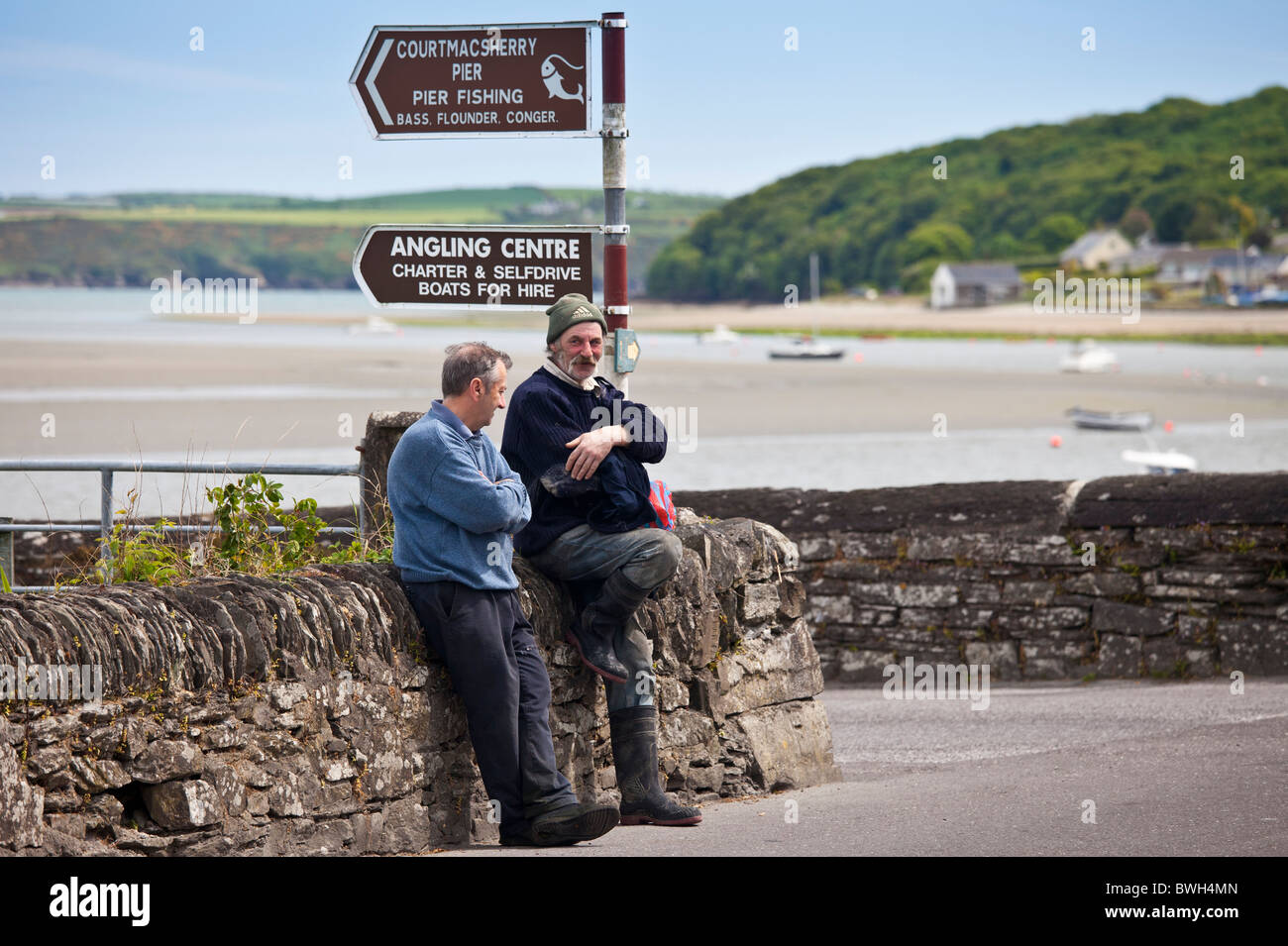 Locali irlandesi gli uomini in chat dal quayside in Courtmacsharry, County Cork, Irlanda Foto Stock