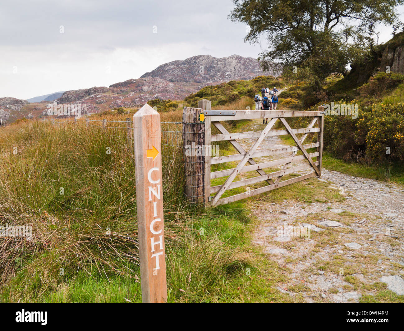 Sentiero segno e open farm gate con la gente che camminava sul percorso per Cnicht montagna nel Parco Nazionale di Snowdonia da Croesor Gwynedd North Wales UK Foto Stock