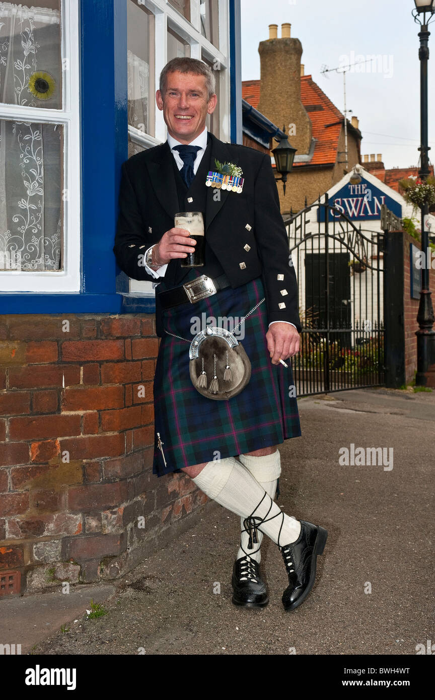 Chiudere verticale su ritratto di un uomo nel tradizionale abito scozzese avente un ultima pinta e sigaretta prima egli si sposano. Foto Stock
