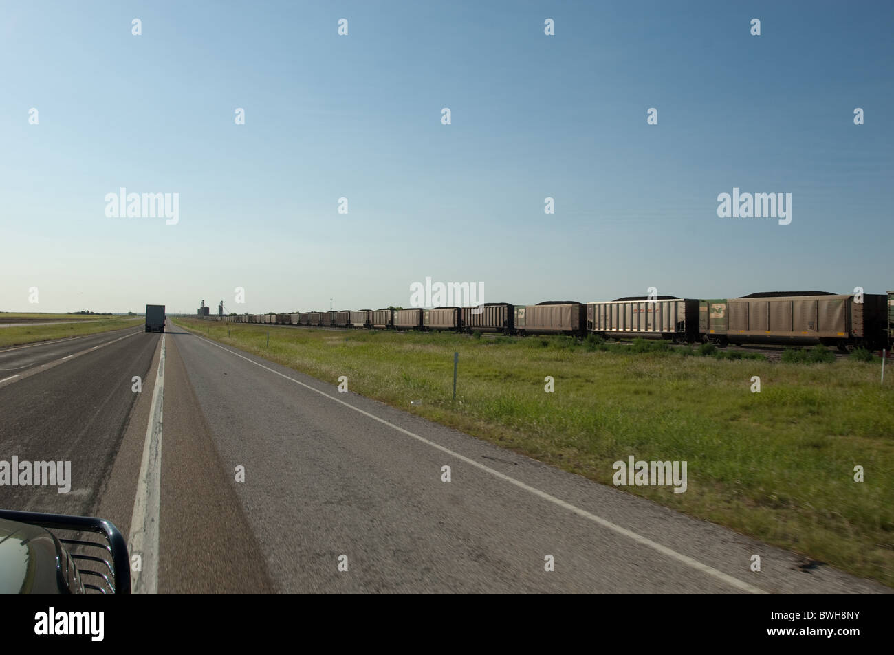 Treno merci rotola lungo le vie in area rurale lungo la US Highway 287 nella porzione di Panhandle del Texas, Stati Uniti d'America Foto Stock