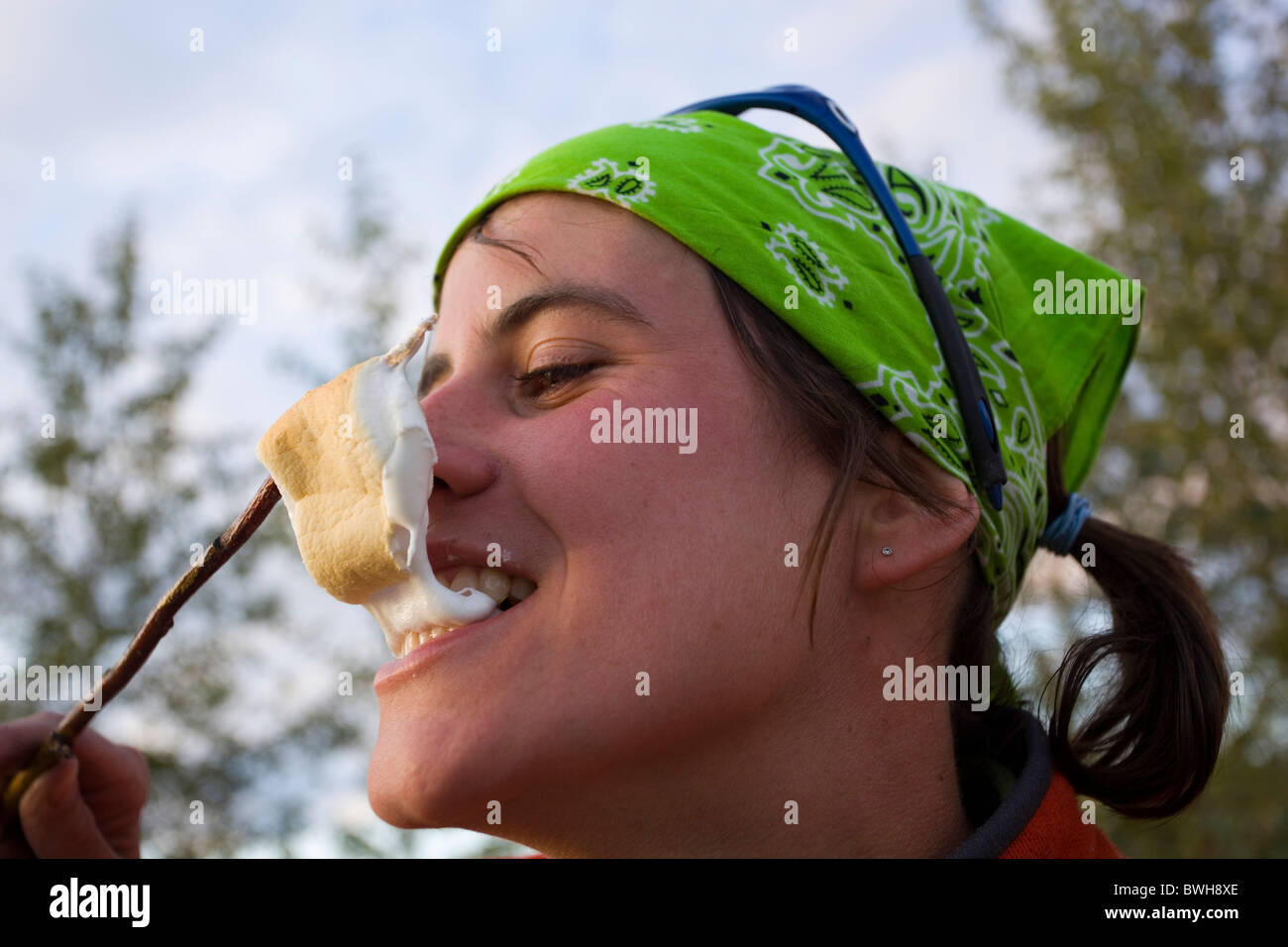 Giovane donna godendo hot, grigliate marshmallow fuso su un bastone, superiore Liard River, Yukon Territory, Canada Foto Stock